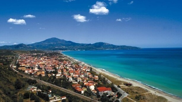 An aerial view of a coastal town with a beach, houses, and mountains in the background. - Apartment in Marina di Ascea near the Beach (Ascea)