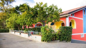 A row of colorful buildings with arched windows and a paved walkway. - Apartment in Marina di Ascea near the Beach (Ascea)