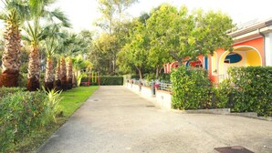 A pathway lined with palm trees and a building with colorful circular windows. - Apartment in Marina di Ascea near the Beach (Ascea)