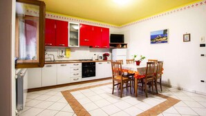 A kitchen with red cabinets, a dining table with chairs, and a tiled floor. - Apartment in Marina di Ascea near the Beach (Ascea)
