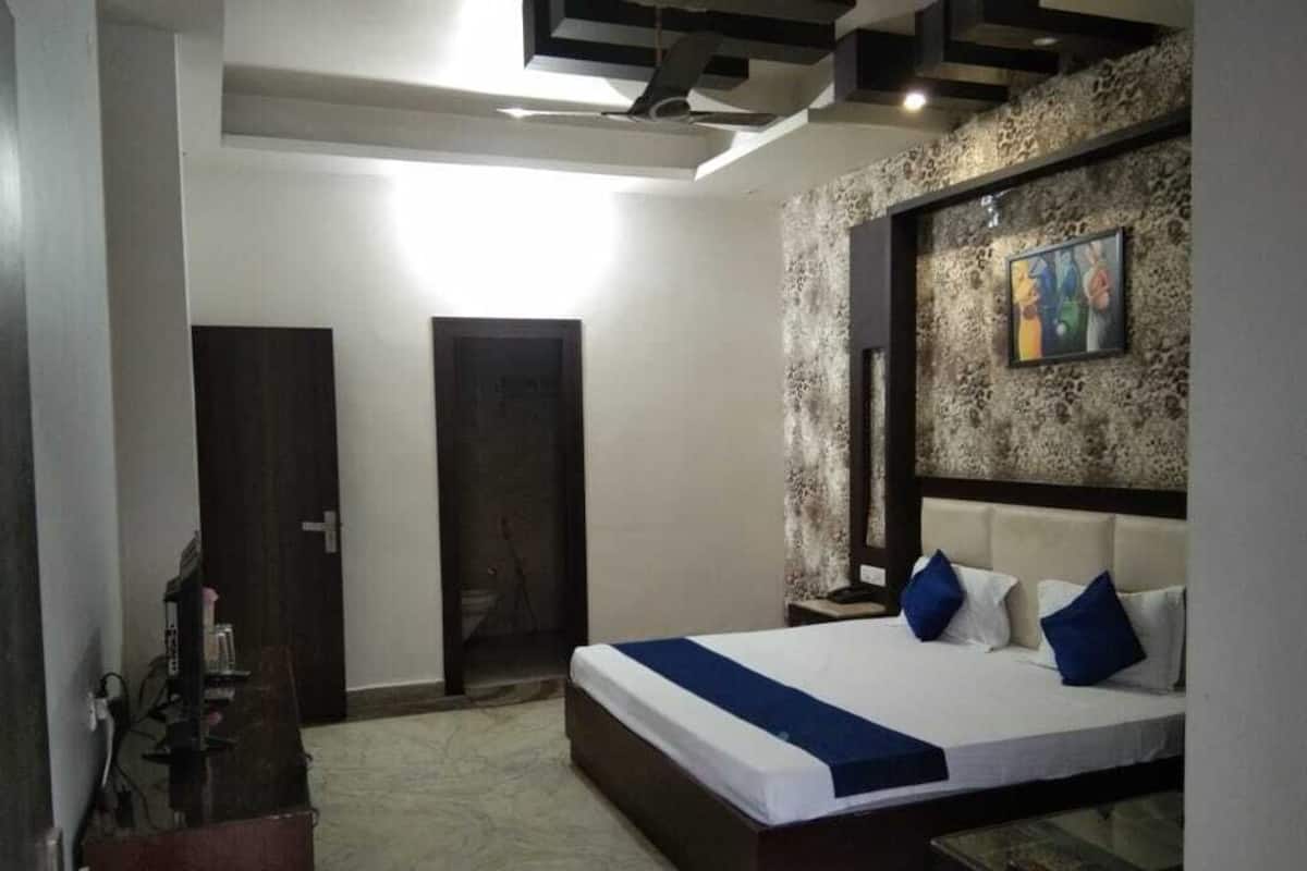 A bedroom with a large bed, a wooden headboard, a stone accent wall, and a painting.