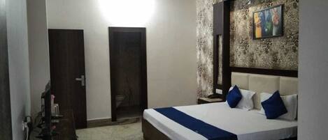 Un dormitorio con una cama grande, cabecera de madera, una pared de acento de piedra y un cuadro.