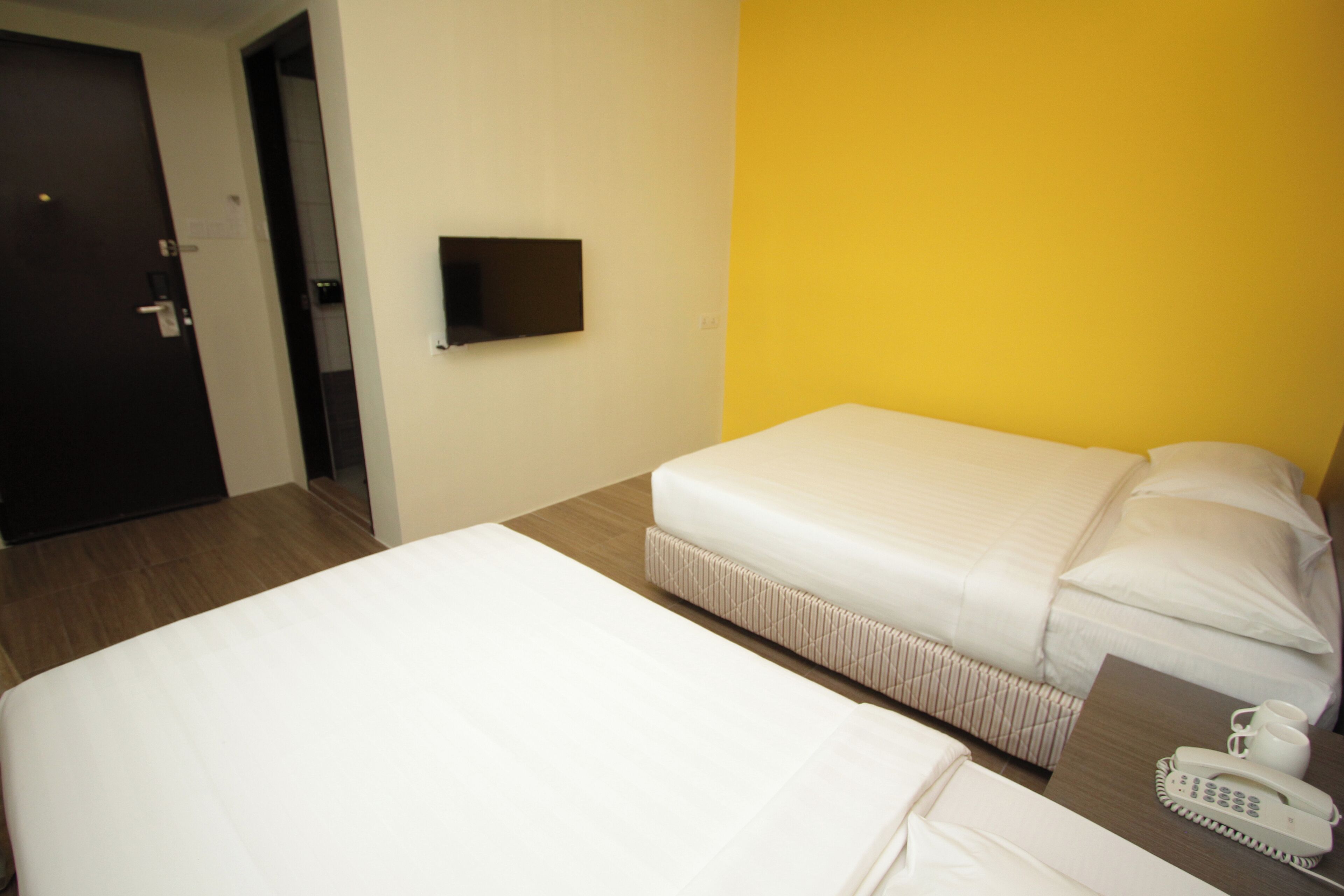 Habitación de hotel con dos camas, un televisor en la pared y un teléfono junto a la cama.