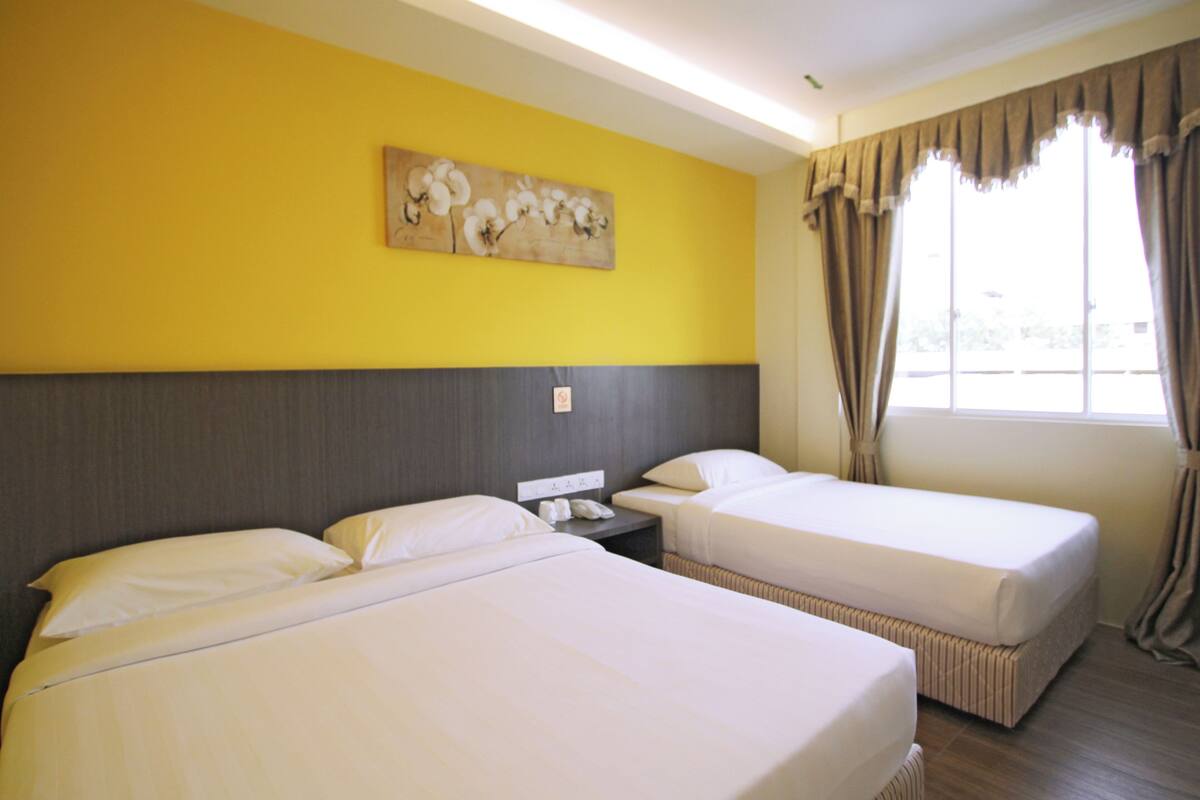 A hotel room with two beds, a nightstand with a phone, and a window with curtains.