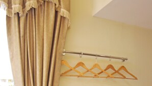 A room with a wooden drying rack, a curtain, and a window with a view of greenery outside. - Signature Inn (Kota Kinabalu)