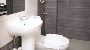 A modern bathroom with a white sink, a toilet, and a glass shower enclosure. - Signature Inn (Kota Kinabalu)