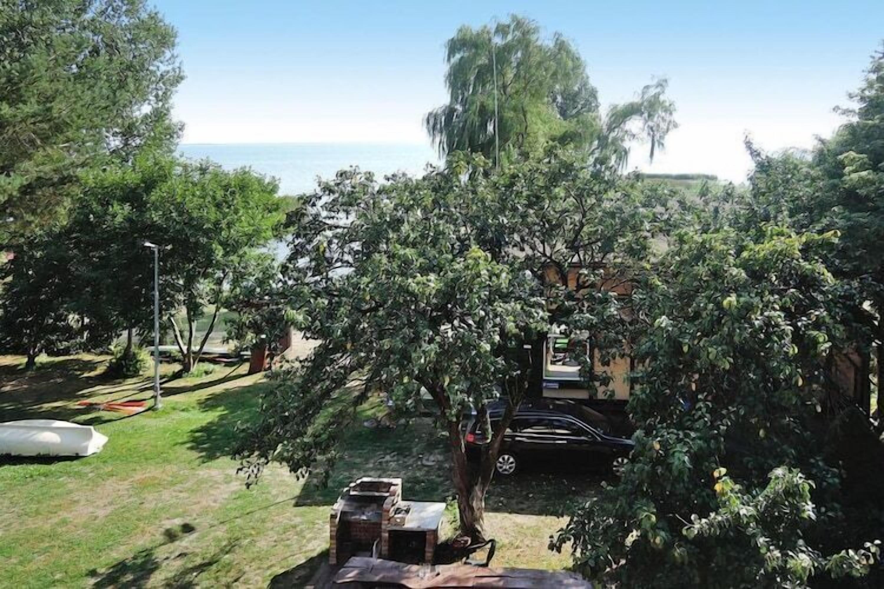 A backyard with a barbecue grill, a hammock, and a car parked nearby.