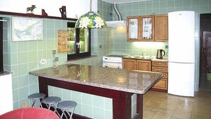 A kitchen with a central island, stools, a refrigerator, and wooden cabinets.
