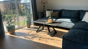 Un salon moderne avec un canapé bleu foncé, une table basse en verre et une plante en pot.