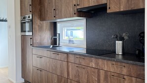 Une cuisine moderne avec des meubles en bois, des appareils électroménagers en acier inoxydable et une fenêtre donnant sur un jardin.