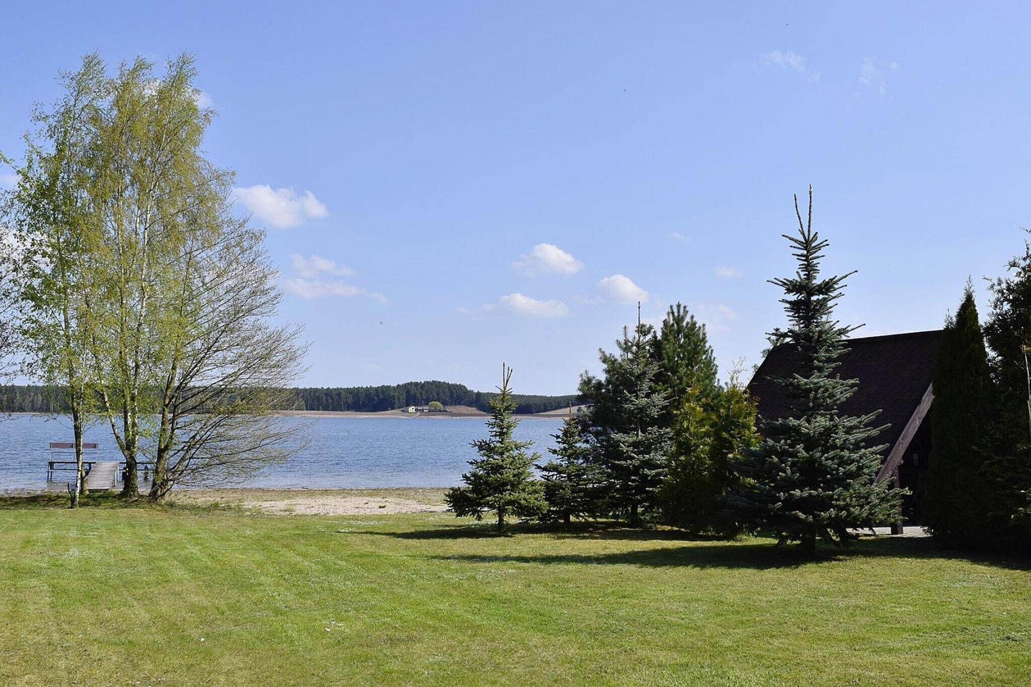 En utsikt över en sjö med en brygga, träd och en byggnad.