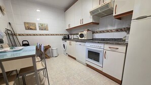 Eine Küche mit weißen Schränken, einer Mikrowelle, einem Backofen und einer Waschmaschine.
