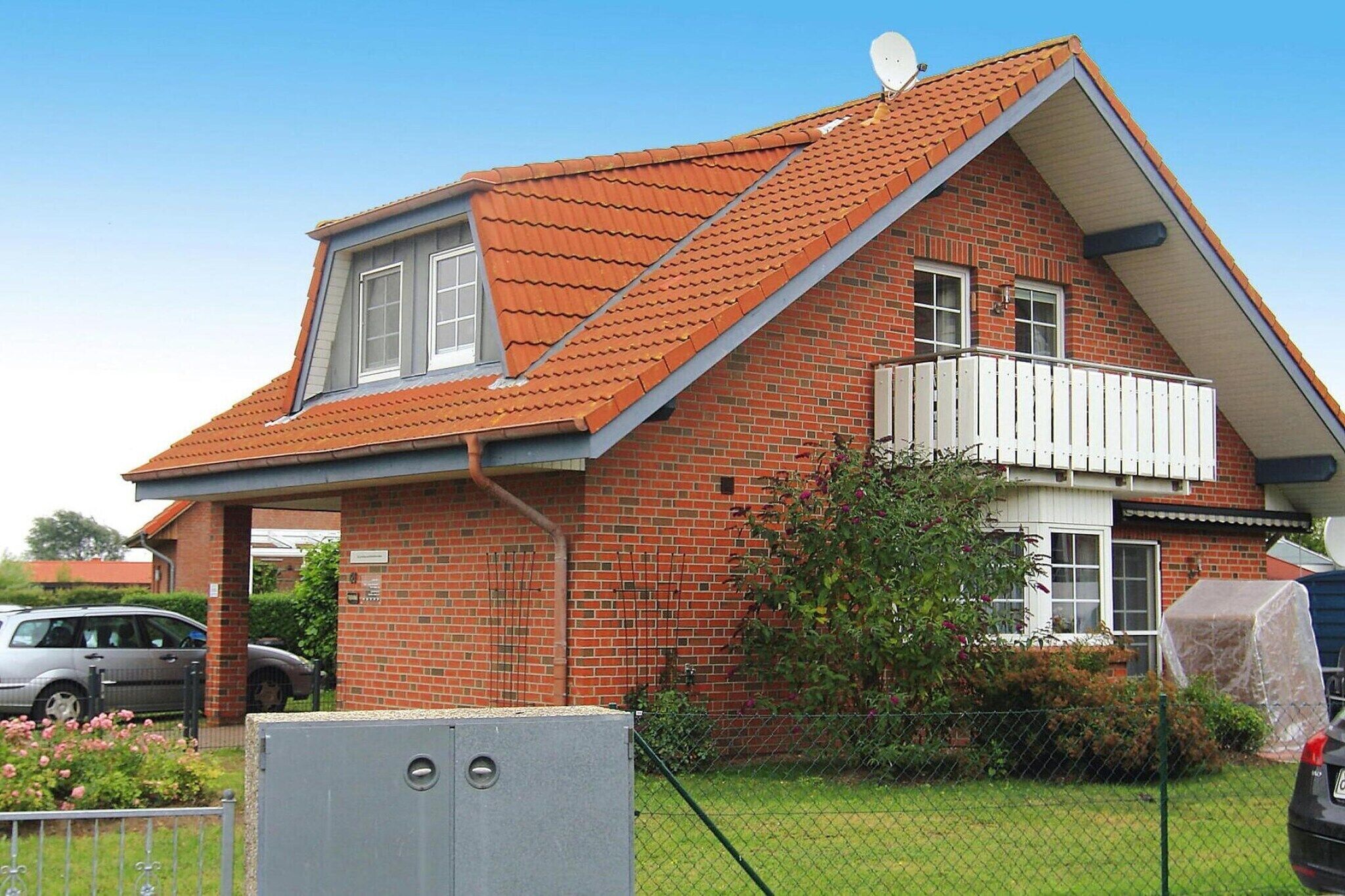 Ein zweigeschossiges Ziegelhaus mit geneigtem Dach, einem Balkon und einer Satellitenschüssel.