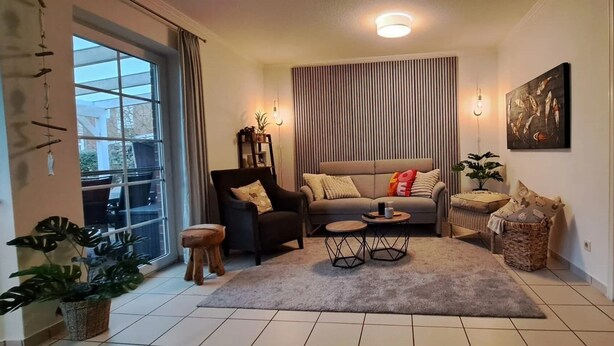 Ein Wohnzimmer mit einer Couch, zwei Beistelltischen, einem Couchtisch und einem großen Fenster.