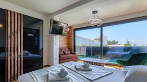 A modern hotel room with a large bed, a TV mounted on the wall, a balcony with a view, and a wooden partition. - Vacation home Rial 2 by Interhome (Fažana)