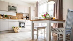 Una cocina moderna con armarios blancos, una encimera de madera y un comedor con sillas a rayas.