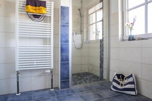 A bathroom with a shower, a towel rack, and a bag on the floor. - Luxushaus Bodden mit Schwimmbereich (Fuhlendorf)
