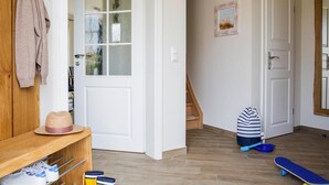 Un couloir avec un banc en bois, un chapeau et une planche à roulettes.