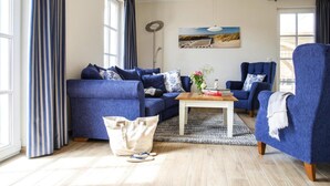 Un salon moderne avec un canapé bleu, une table basse et un tableau accroché au mur.