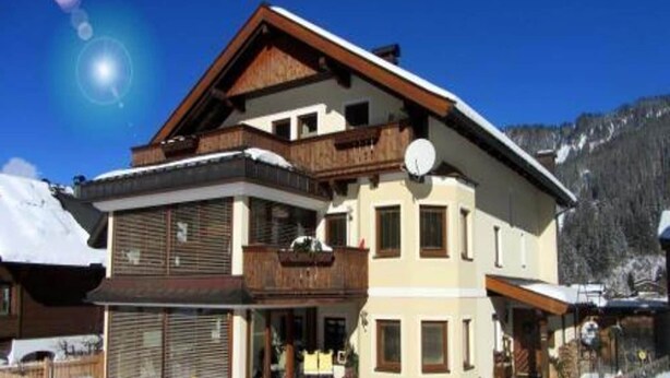 Eine zweistöckige Chalet mit Holzbalkon, Garage und Bergblick.