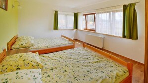 Una habitación con dos camas de madera, un radiador y una ventana con cortinas.