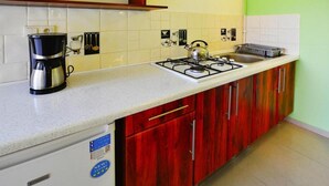 Una cocina con estufa a gas, cafetera y armarios de madera.