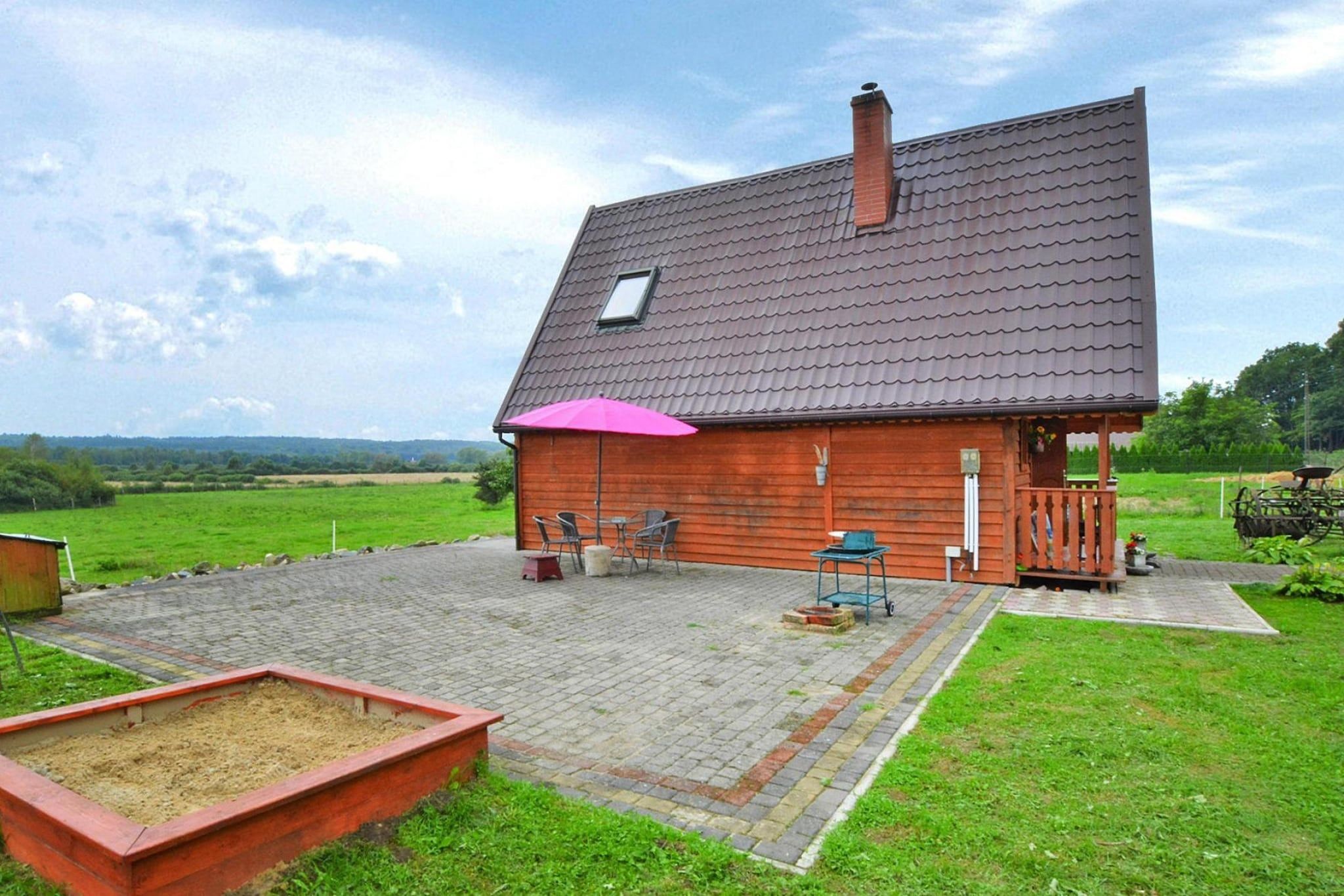 Une maison en bois avec un toit en tuiles, une terrasse avec des meubles d’extérieur et un jardin.