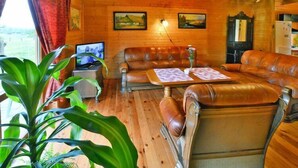 A cozy wooden interior with leather sofas, a coffee table, and a television. - Holiday Home in Swiecianowo near Lake Beach (Swiecianowo)