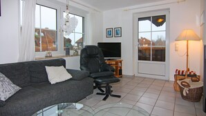 A living room with a grey sofa, a black leather chair, a glass coffee table, a flat-screen TV, and a lamp. - Apartment in Petersdorf for 6 Personen (Petersdorf)