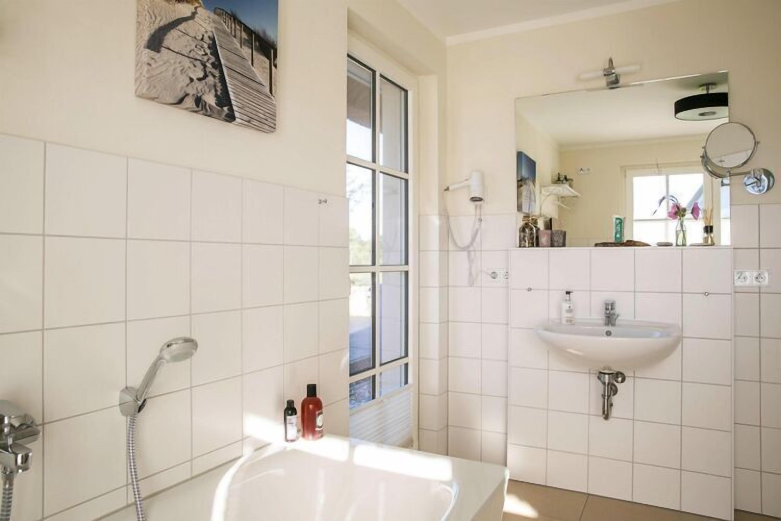Une salle de bain avec une baignoire, un lavabo et un miroir.