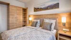 Une chambre à coucher avec un grand lit, une tête de lit en bois, deux lampes de chevet, une table de chevet et une armoire.