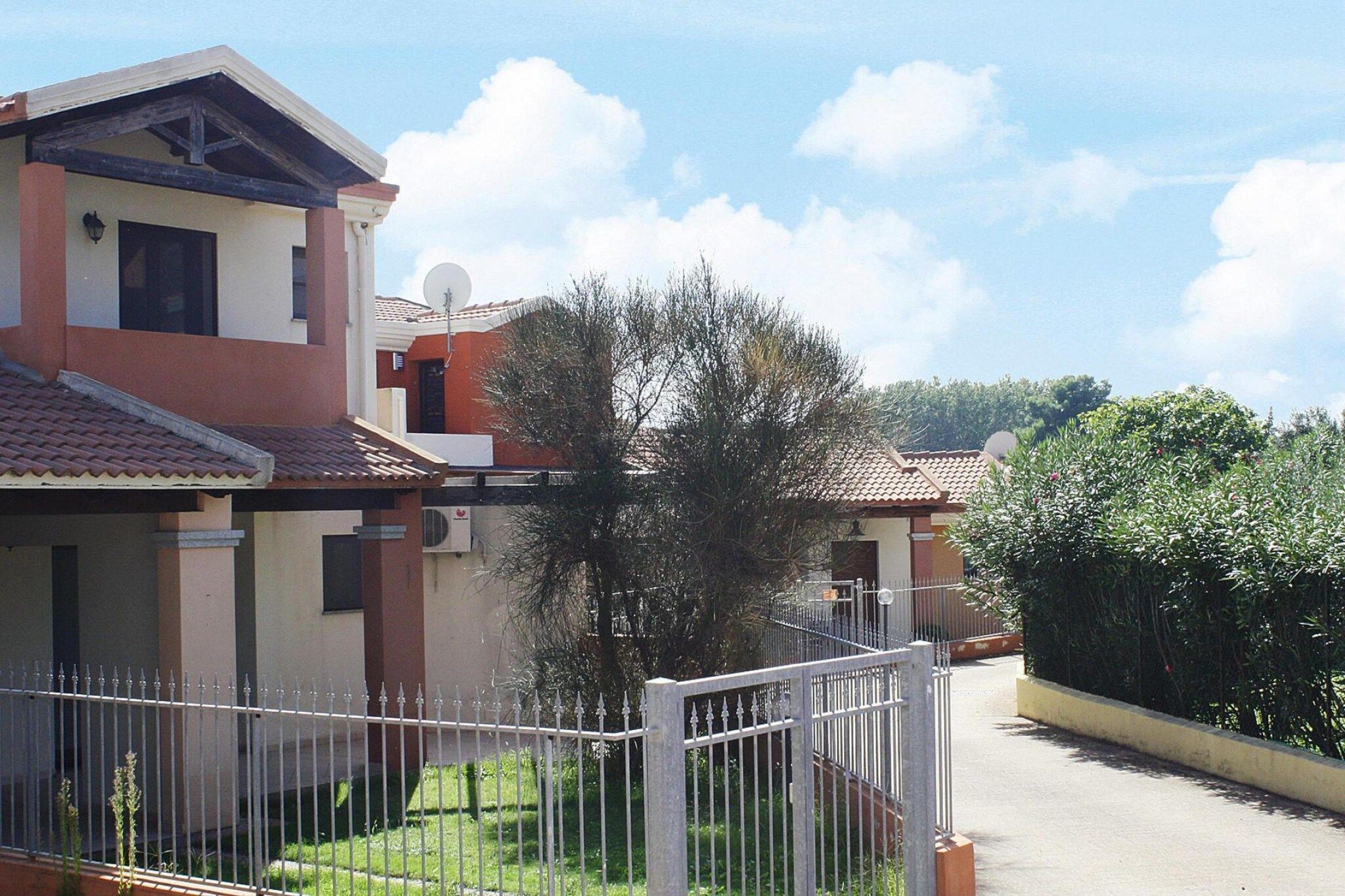 Área residencial com casas, cerca branca e céu claro.