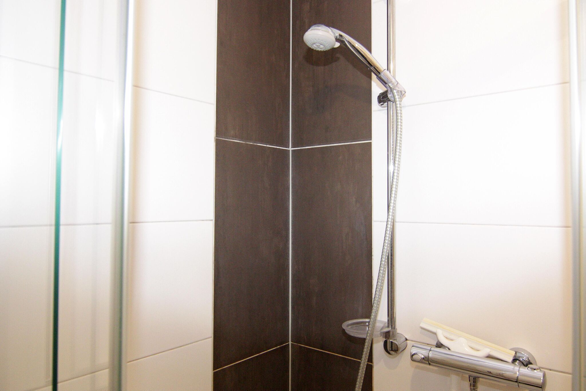 A shower with a handheld showerhead and a handheld shower attachment.