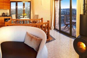 Un salon confortable avec un canapé, une table à manger et des chaises, une cheminée et un balcon offrant une vue agréable.