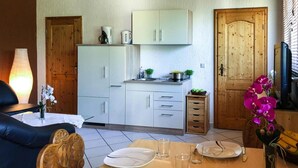 Un espace de vie compact comprenant un coin repas, une kitchenette et une porte en bois.