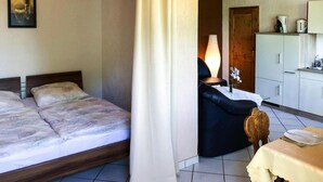 Une chambre d’hôtel avec deux lits, un coin repas comprenant une table et des chaises, et une kitchenette.