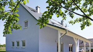 Una casa moderna de dos pisos con porche cubierto y cochera.