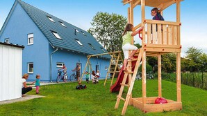 Puinen leikkialue, jossa on liukumäki ja kiipeilyseinä, sijaitsee takapihalla.