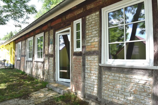 A building with multiple windows, brick walls, and a grassy area in front.