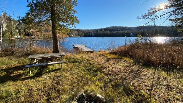A lakeside picnic area with a wooden bench and a dock extending into the water. - Country Chalet with Lakefront (Chertsey)