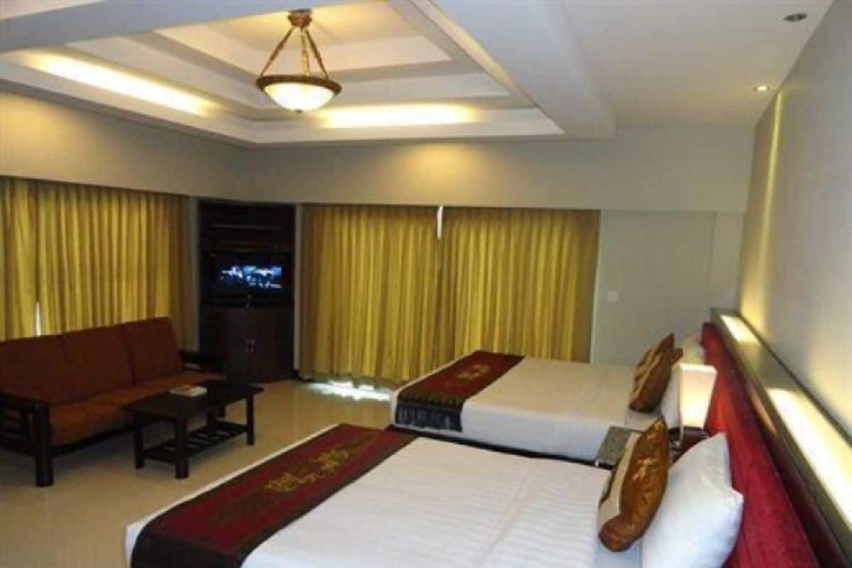 Habitación de hotel con dos camas, un sofá, un televisor y cortinas.