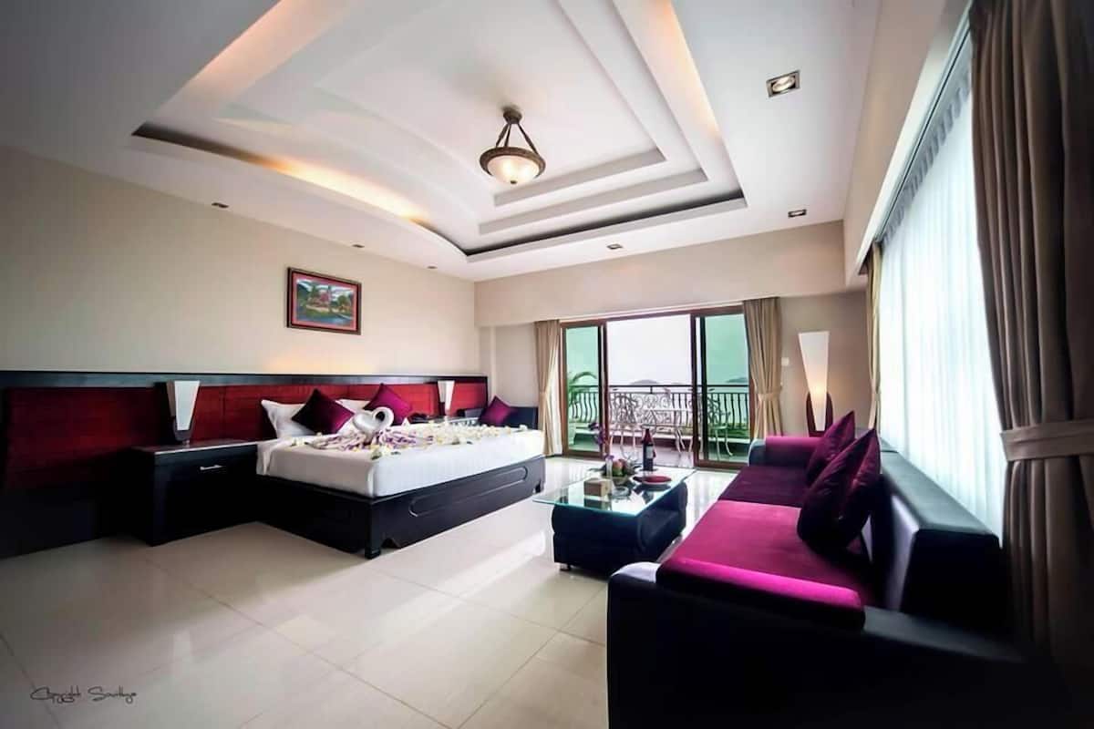 Una habitación de hotel moderna con una cama grande, un sofá, una mesa de centro de vidrio y un balcón con vistas.