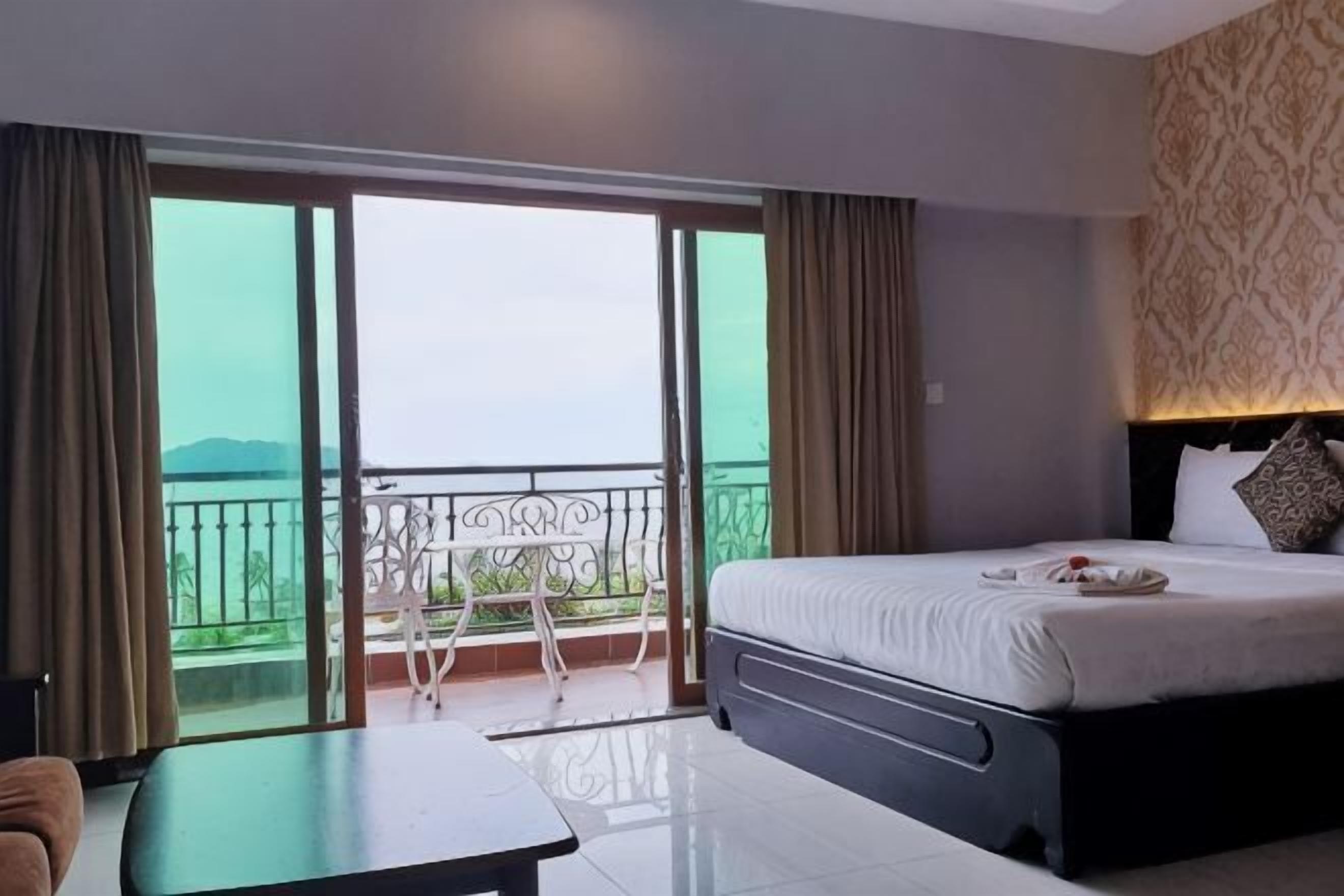 Habitación de hotel con cama, una mesa, una silla, balcón con vistas y pared decorada.