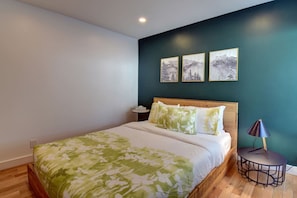 Un dormitorio con una cama, una mesita de noche, una lámpara y tres cuadros en la pared.
