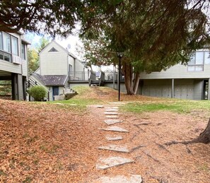 A pathway leading to a building with a sloped roof and a covered porch.