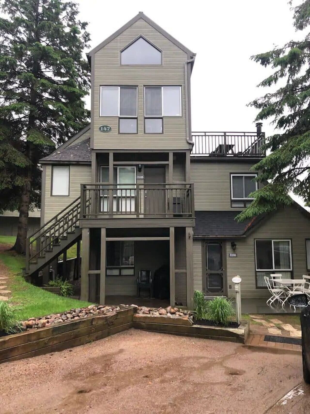 Een tweelaags huis met een balkon, een overdekte veranda en een oprit.