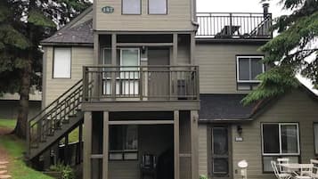 Een tweelaags huis met een balkon, een overdekte veranda en een oprit.