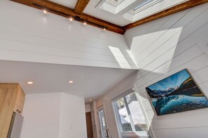 Ein modernes Interieur mit weißen Wänden, Holzbalken, Oberlichtern und einem großen Fenster.