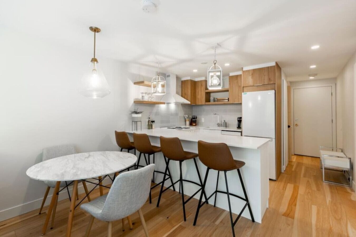 Une cuisine moderne dotée d’un îlot central, de tabourets de bar et de luminaires suspendus.