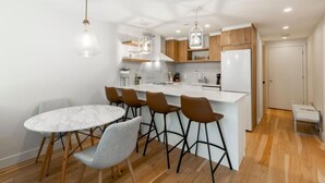 Une cuisine moderne dotée d’un îlot central, de tabourets de bar et de luminaires suspendus.